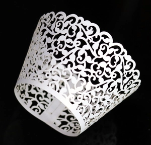 Close-up of white laser-cut vine patterns on decorative cupcake paper wrappers