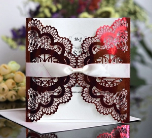 Macro detail of laser cut gold wedding invitation with satin bow and intricate patterns
