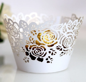 Intricate laser-cut white rose pattern cupcake wrapper with a gold foil candy