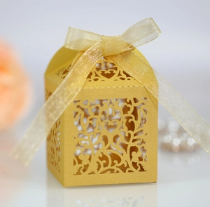 Detail of laser-cut heart pattern on gold candy box with organza ribbon bow
