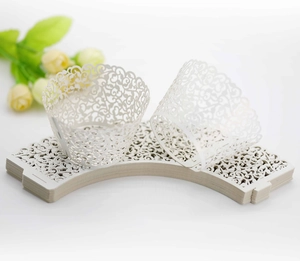 Macro shot of ivory laser-cut cupcake wrappers with elegant hollow lace floral patterns