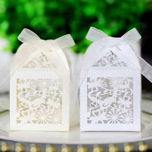 Laser-cut floral and bird candy boxes with organza ribbon on a gold-rimmed plate