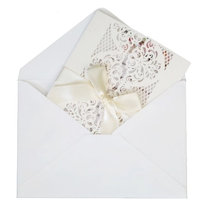 White laser-cut wedding invitation set with floral petal patterns and satin ribbon