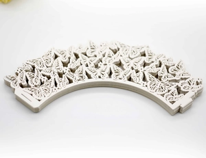 Macro view of laser-cut ivory butterfly cupcake wrappers for wedding cake decorations