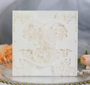 Detailed laser-cut ivory wedding invitation cover with elegant floral patterns on silk