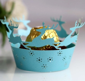 Light blue laser-cut Christmas cupcake wrappers with reindeer and snowflake patterns