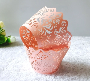 Pink laser cut cupcake wrappers with floral patterns and wavy edges for wedding decor