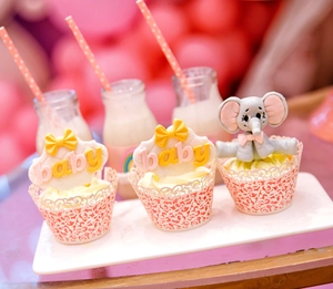 Close-up of pink laser-cut cupcake wrappers and baby elephant toppers for parties