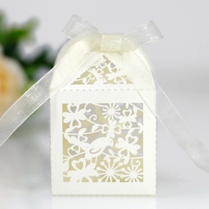 Detail view of laser-cut white wedding candy box with bird patterns and ribbon bow