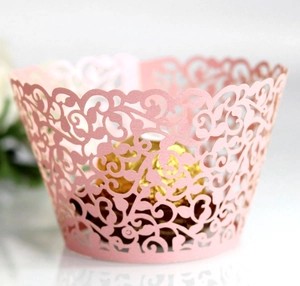 Close-up of pink laser-cut cupcake wrapper with intricate floral vine hollow pattern