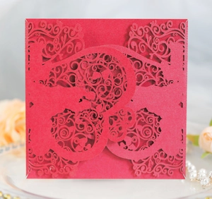 Detailed laser-cut pattern on red wedding invitation with floral and heart motifs