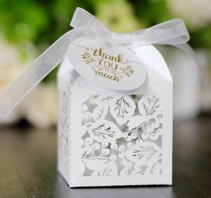 Détail de la boîte cadeau ajourée blanc nacré avec ruban de soie et carte de remerciement