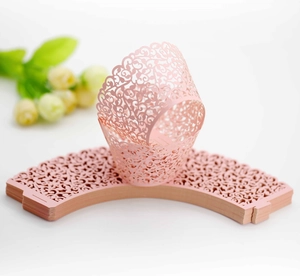 Macro detail of pink laser-cut cupcake wrappers with floral lace patterns for weddings