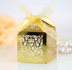 Detail of laser-cut heart pattern on golden favor box with a satin ribbon bow