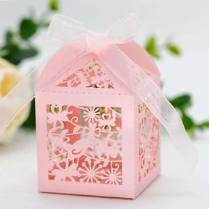 Macro detail of laser-cut pink gift box with floral bird patterns and white ribbon bow