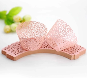 Detailed laser-cut pink cupcake wrappers with elegant vine patterns for wedding decor