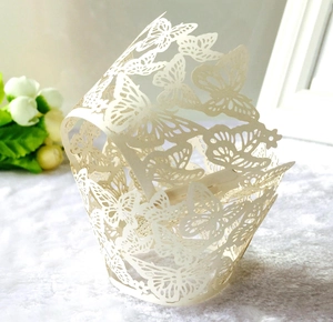 Detail of laser-cut butterfly cupcake wrapper in white with intricate hollowed patterns