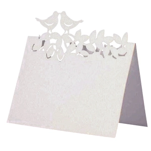 Détail d'un marque-place blanc découpé au laser avec oiseaux et motifs floraux