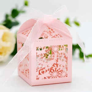Detail of pink laser-cut paper gift box featuring intricate floral and bird patterns