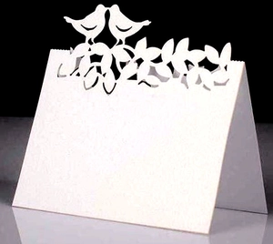 Détail du marque-place blanc découpé au laser avec motif arbre et oiseaux pour mariage