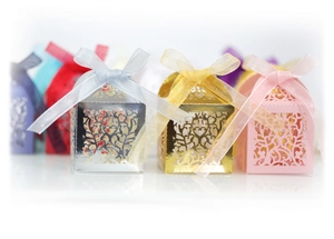 Laser-cut wedding favor boxes with intricate heart patterns and elegant organza ribbons