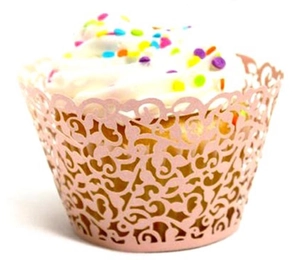 Pink laser-cut cupcake wrapper with intricate vine pattern on a white background