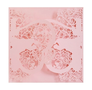 Macro view of pink laser-cut wedding invitation with elegant floral hollow patterns