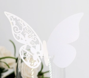 Macro shot of white laser-cut butterfly card with intricate floral patterns for weddings