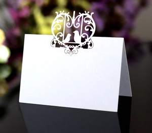 Detailed laser-cut heart and birds pattern on a white wedding place card