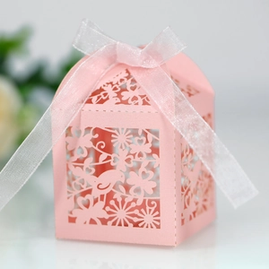 Close-up of pink laser-cut candy gift box with birds pattern and white ribbon bow