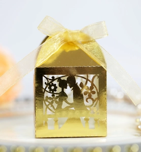 Detail einer goldenen lasergeschnittenen Hochzeitsbox mit Silhouetten und Schleife