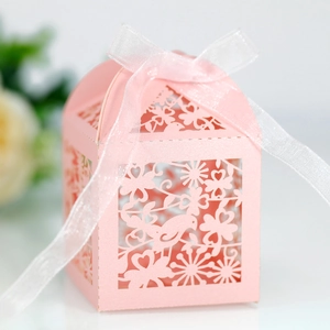 Macro detail of laser-cut pink gift box with bird patterns and white organza ribbon