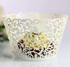 Detail of laser-cut vine patterns on white paper cupcake wrapper with gold chocolate decor