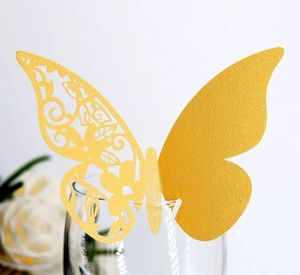 Macro shot of gold glitter 3D butterfly place card with laser-cut floral wing on glass