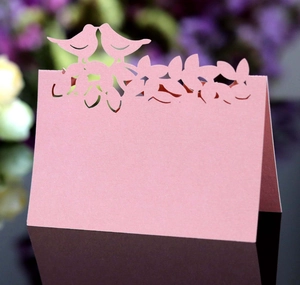 Détail du marque-place rose découpé au laser avec deux oiseaux sur surface noire