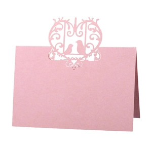 Pink laser-cut place card with bird and flower patterns on a white background