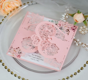 Detail of laser-cut floral hollow pattern on pink wedding invitation card with roses