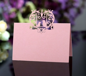 Detail of laser-cut place card featuring elegant bird patterns in dusty pink pearlescent paper