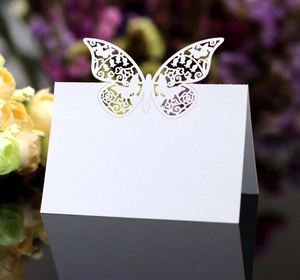 Macro detail of laser-cut white butterfly place cards with elegant hollow patterns