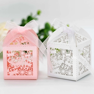 Detail of laser-cut flower and bird patterns on pink and white wedding favor boxes
