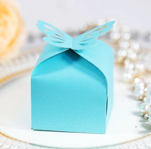 Detail of light blue wedding favor box featuring laser-cut butterfly on a ceramic plate