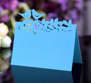 Détail du marque-place découpé au laser avec oiseaux et fleurs sur papier cartonné bleu