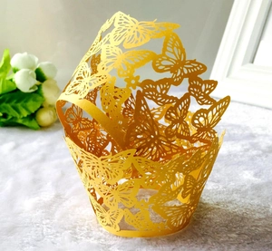 Detail view of yellow butterfly laser-cut cupcake wrappers on a soft white decorative rug