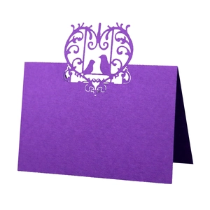 Detail of purple laser-cut place card with bird heart design for wedding tables