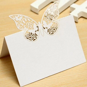 Macro shot of white laser-cut butterfly place card with floral patterns on wooden table