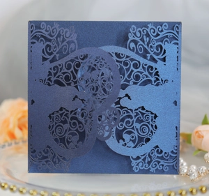 Macro shot of navy blue laser-cut wedding invitation with intricate floral and bird patterns