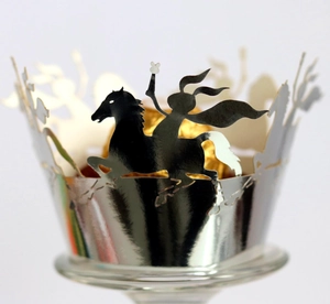 Macro detail of laser-cut silver cupcake wrapper with hero horse silhouette design
