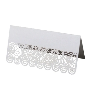 Close-up of laser-cut lace pattern on white folded paper wedding place card for table