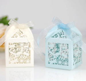 Detail of laser-cut wedding favor boxes with bird patterns and elegant ribbon bows
