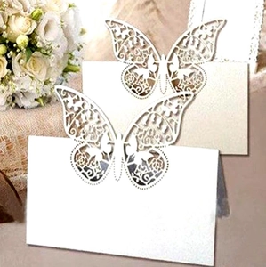 Detail of white laser-cut butterfly place cards featuring intricate floral wing patterns